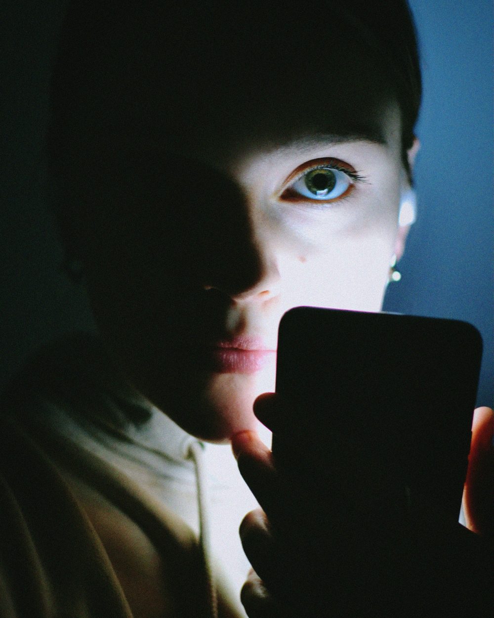 A face lit only by a phone screen in the dark